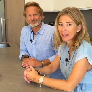 Photo de Véronique de Bernonville et Jeff Gardair assis contre un îlot de cuisine, souriants. ils sont habillés en bleu ciel.