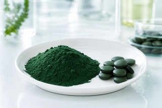 Spiruline pure en poudre et comprimés sur une coupelle blanche