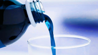 Gros plan d’un complément alimentaire bleu (phycocyanine) en cours de versement dans un verre.